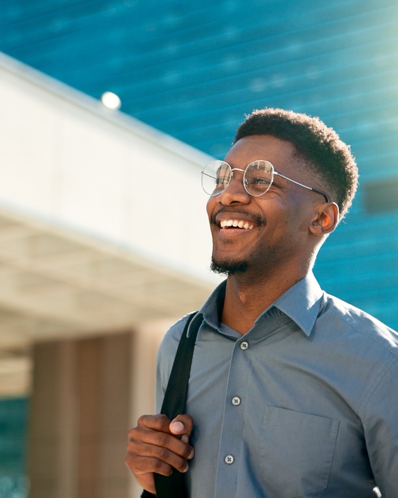 Business, happy and walking black man on city journey, commute trip and realtor smile on way to office building. Happiness, career expert and African real estate agent on morning travel in Nigeria Smiling woman looking at her phone while using laptop to book a trip